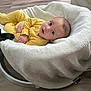Mateo is registered to the contest to win money with this photo: baby, infant, yellow_clothing, blanket, baby_seat, floor, wooden_floor, cozy, indoor, child, portrait, looking_up, curious, soft_texture, comfortable, cute, newborn, resting, casual, home