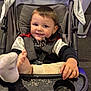 toddler, child, stroller, smile, foot, clothing, seat, tray, crumbs, indoor, playful, baby, person, young_child, casual, happy, black_jacket, beige_pants, seatbelt, hand