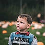 child, boy, pumpkin_patch, backpack, hoodie, outdoor, autumn, curious, portrait, grass, fall, nature, bokeh, casual_clothing, young, daylight, seasonal, cute, expression, youth