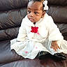 toddler, child, baby, dress, white_jacket, hair_bows, black_shoes, sitting, leather_couch, curious, portrait, indoors, cute, fashion, young_child, person, girl, clothing, footwear, seated