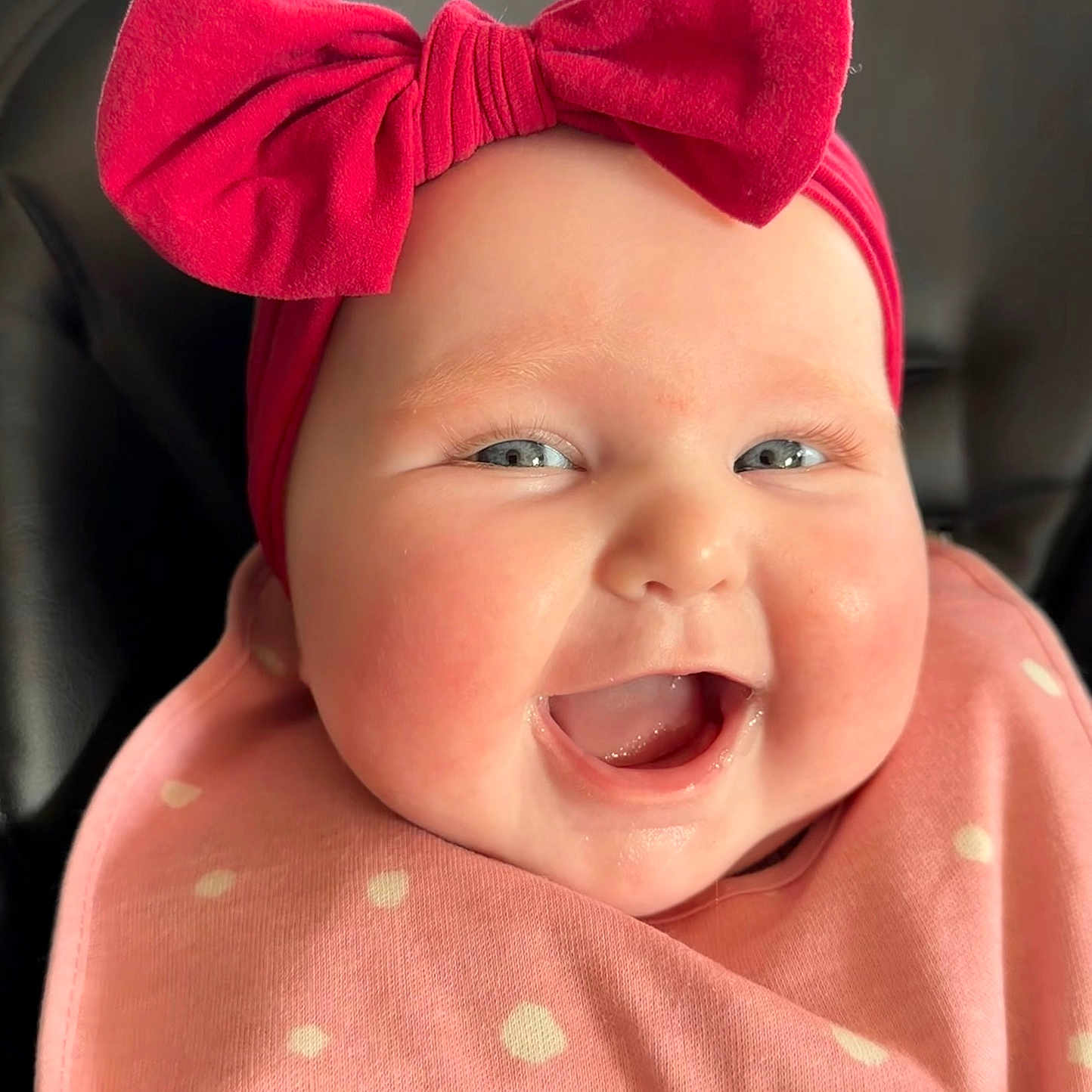Charli is registered to the contest to win money with this photo: baby, bib, bow, cheeks, child, close_up, clothing, cute, face, happy, headband, indoors, infant, joy, person, pink, polka_dot, portrait, skin, smiling