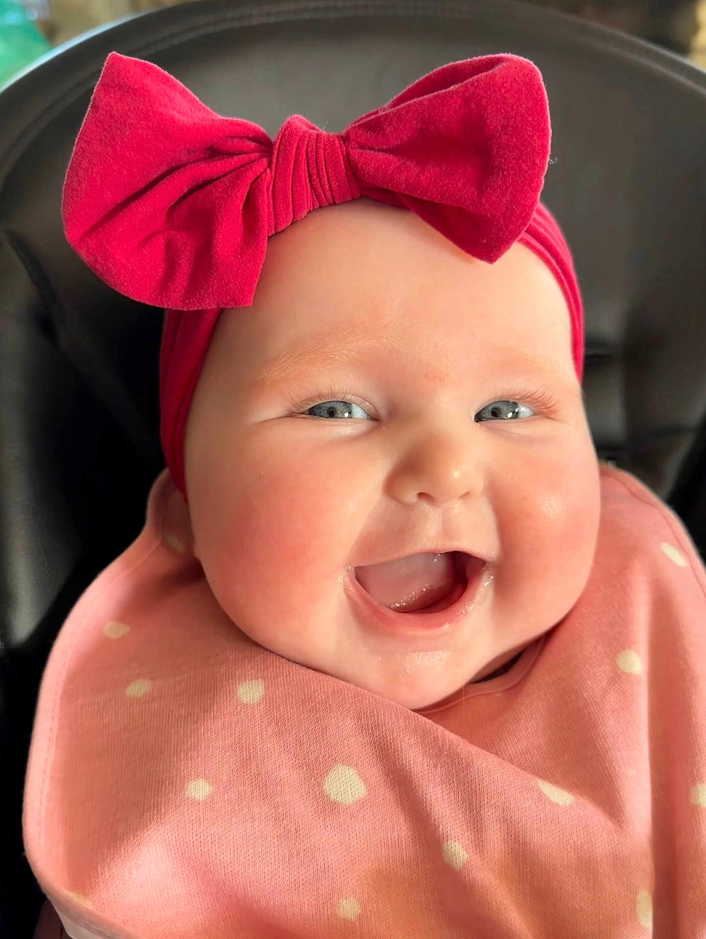 Charli is registered to the contest to win money with this photo: baby, smiling, face, headband, pink, bow, bib, polka_dot, cheeks, close_up, infant, happy, cute, child, portrait, clothing, skin, person, indoors, joy