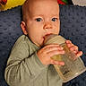 baby, infant, child, bottle, feeding, formula, sitting, lying_down, wide_eyed, face, hands, gray_outfit, blanket, nursery, toys, colorful, indoors, portrait, close_up, happy