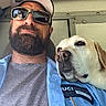 man, beard, sunglasses, cap, dog, golden_retriever, pet, animal, portrait, selfie, indoor, shirt, uniform, badge, vehicle, companion, relaxed, casual, friendship, closeup