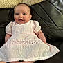baby, infant, smile, pink_dress, lace, couch, leather, happy, child, portrait, sitting, cute, young_child, indoors, person, apparel, face, human, small_child, adorable