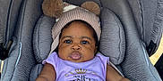 Angel is registered to the contest to win money with this photo: baby, infant, car_seat, hat, pom_poms, purple_clothing, straps, outdoor, child, seatbelt, cute, face, person, sitting, expression, headwear, safety, young_child, portrait, daylight