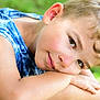 blue_clothing, boy, casual, child, closeup, curly_hair, daylight, face, green_background, happy, nature, outdoor, person, portrait, relaxed, resting, skin, sleeveless_shirt, smile, young