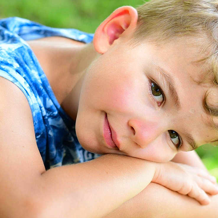 Nicola a rejoint le concours — aidez-le/la à gagner de superbes lots ! blue_clothing, boy, casual, child, closeup, curly_hair, daylight, face, green_background, happy, nature, outdoor, person, portrait, relaxed, resting, skin, sleeveless_shirt, smile, young