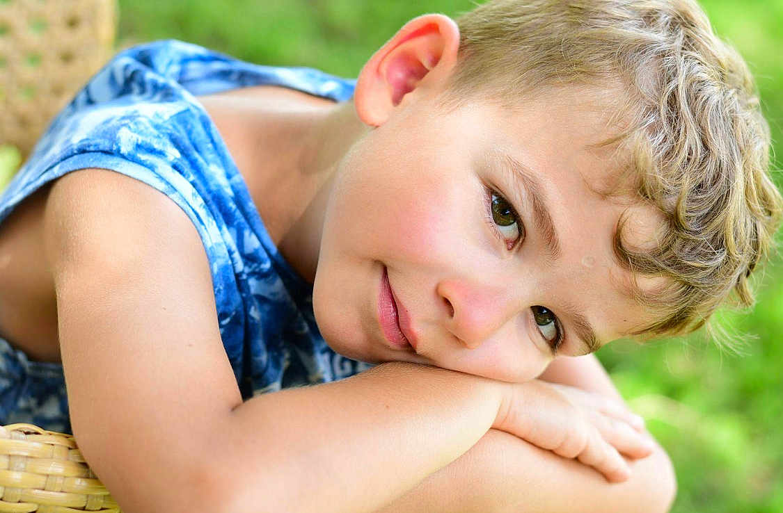 Nicola a rejoint le concours — aidez-le/la à gagner de superbes lots ! blue_clothing, boy, casual, child, closeup, curly_hair, daylight, face, green_background, happy, nature, outdoor, person, portrait, relaxed, resting, skin, sleeveless_shirt, smile, young