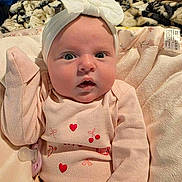 Lavinia joined the competition — help win amazing prizes! baby, infant, headband, bow, pink_clothing, hearts, cherries, blanket, plush, cute, wide_eyes, soft_texture, indoors, child, portrait, clothing, pacifier, expression, cozy, lying_down