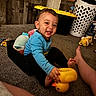 toddler, child, smiling, rubber_duck, toy, basket, carpet, indoor, laundry_basket, clothing, person, happy, floor, foot, wooden_wall, play, cute, young_child, home, casual