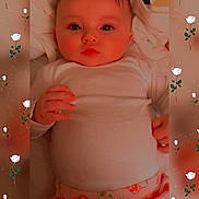 Heather joined the competition — help win amazing prizes! baby, infant, white_shirt, floral_pants, lying_down, cute, face, hands, roses, frame, pattern, soft, cozy, portrait, child, young_baby, indoors, blanket, skin, expression