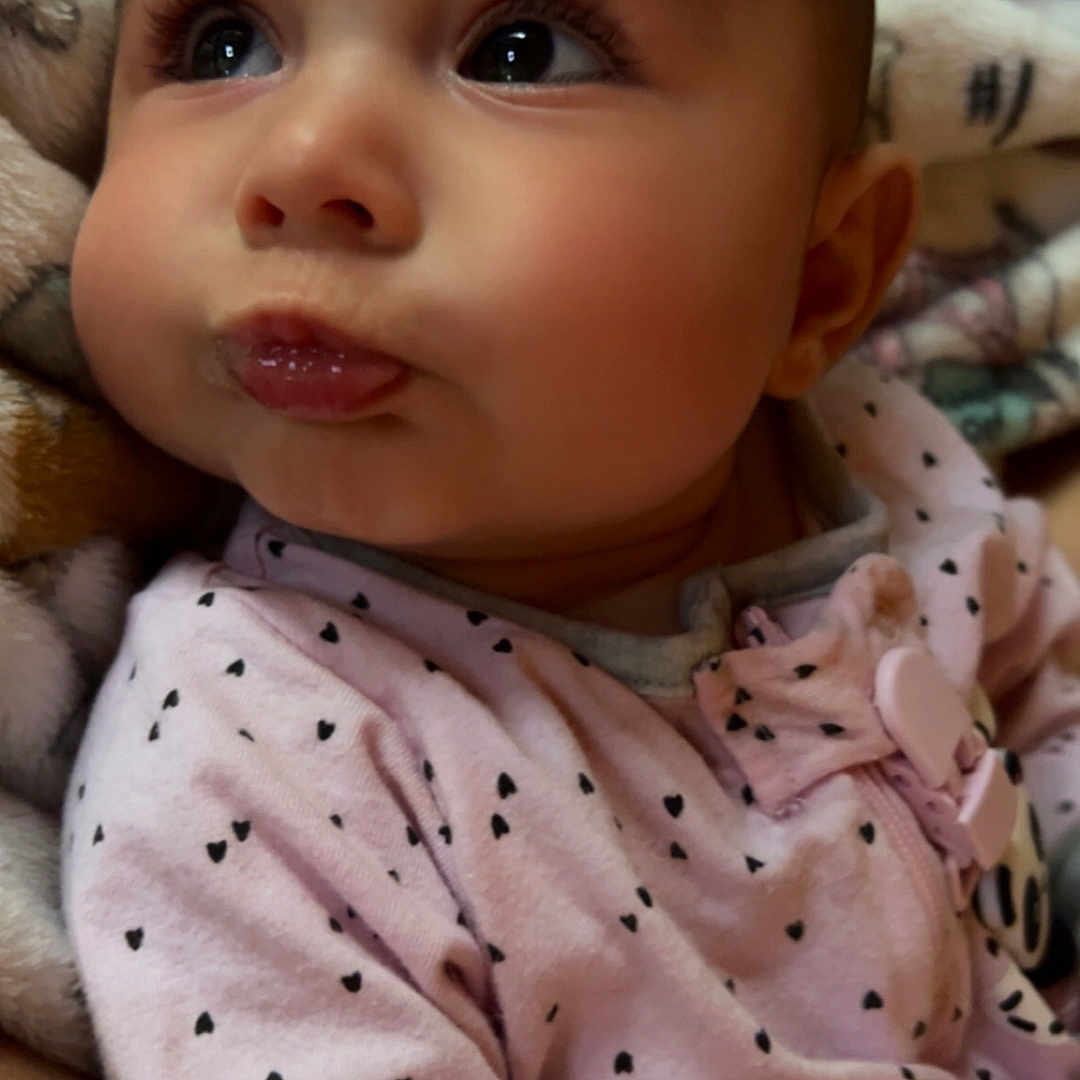 Maya is registered to the contest to win money with this photo: baby, blanket, bodypart, clothing, ear, face, finger, hand, happy, hat, head, knitwear, mouth, newborn, pattern, person, photography, portrait, smile, sweater