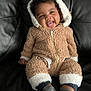 Elias joined the competition — help win amazing prizes! baby, child, smile, happy, fuzzy_outfit, bear_ears, hooded_jumpsuit, socks, leather_couch, seated, portrait, indoor, cute, infant, cozy, warm_clothing, zipper, black_background, small_child, playful