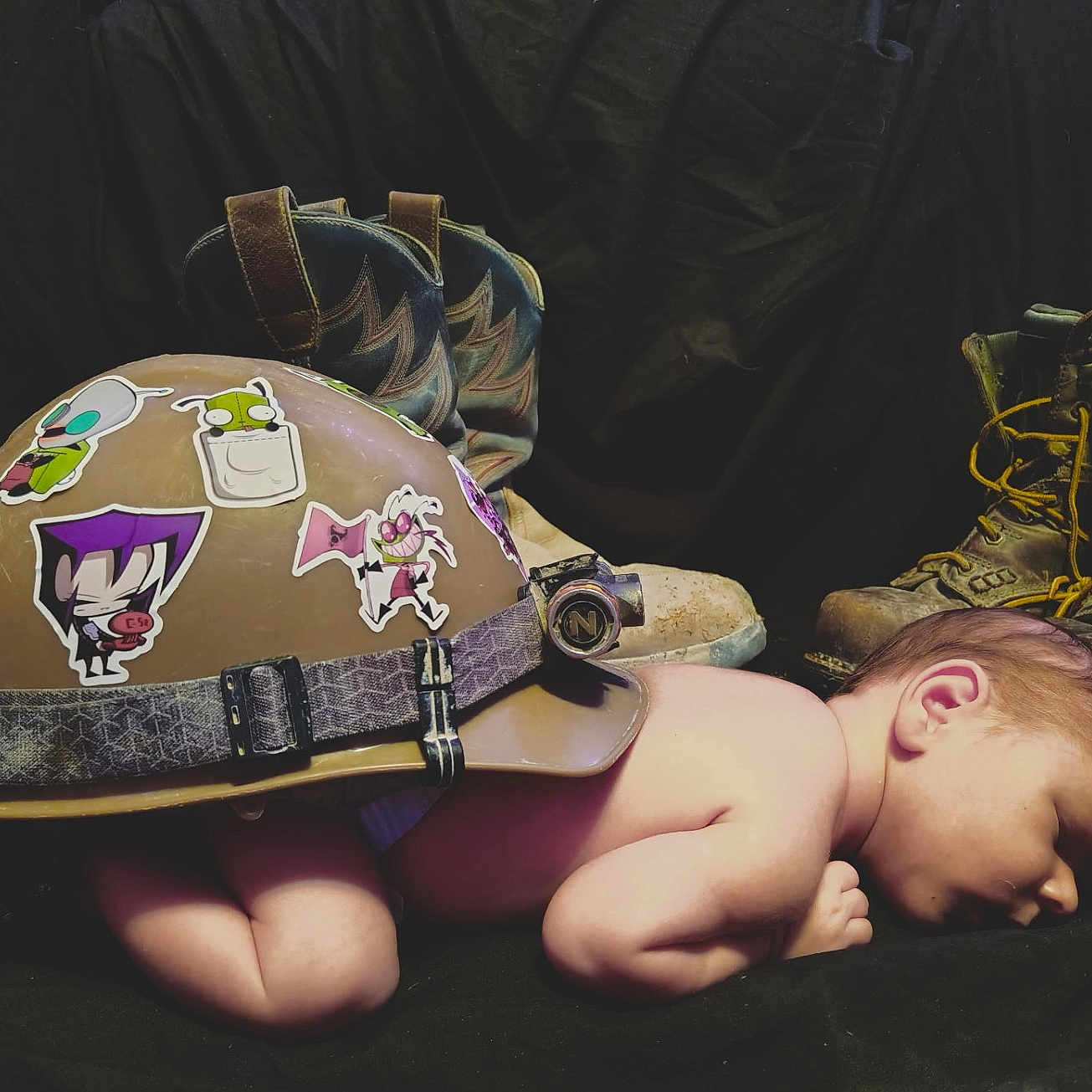 Ridge is registered to the contest to win money with this photo: baby, bare_skin, boots, child, contrast, cute, dark_background, footwear, hard_hat, helmet, infant, newborn, peaceful, protection, rest, side_profile, sleeping, stickers, studio, work_boots