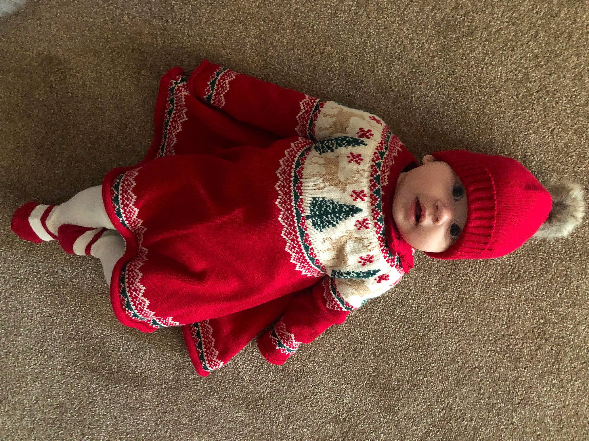 Jessica is registered to the contest to win money with this photo: baby, baby_toddler_clothing, carmine, child, costume_hat, fashion_accessory, floor, flooring, hat, headgear, headwear, human_body, knit_cap, magenta, pattern, person, sitting, sleeve, sock, toddler