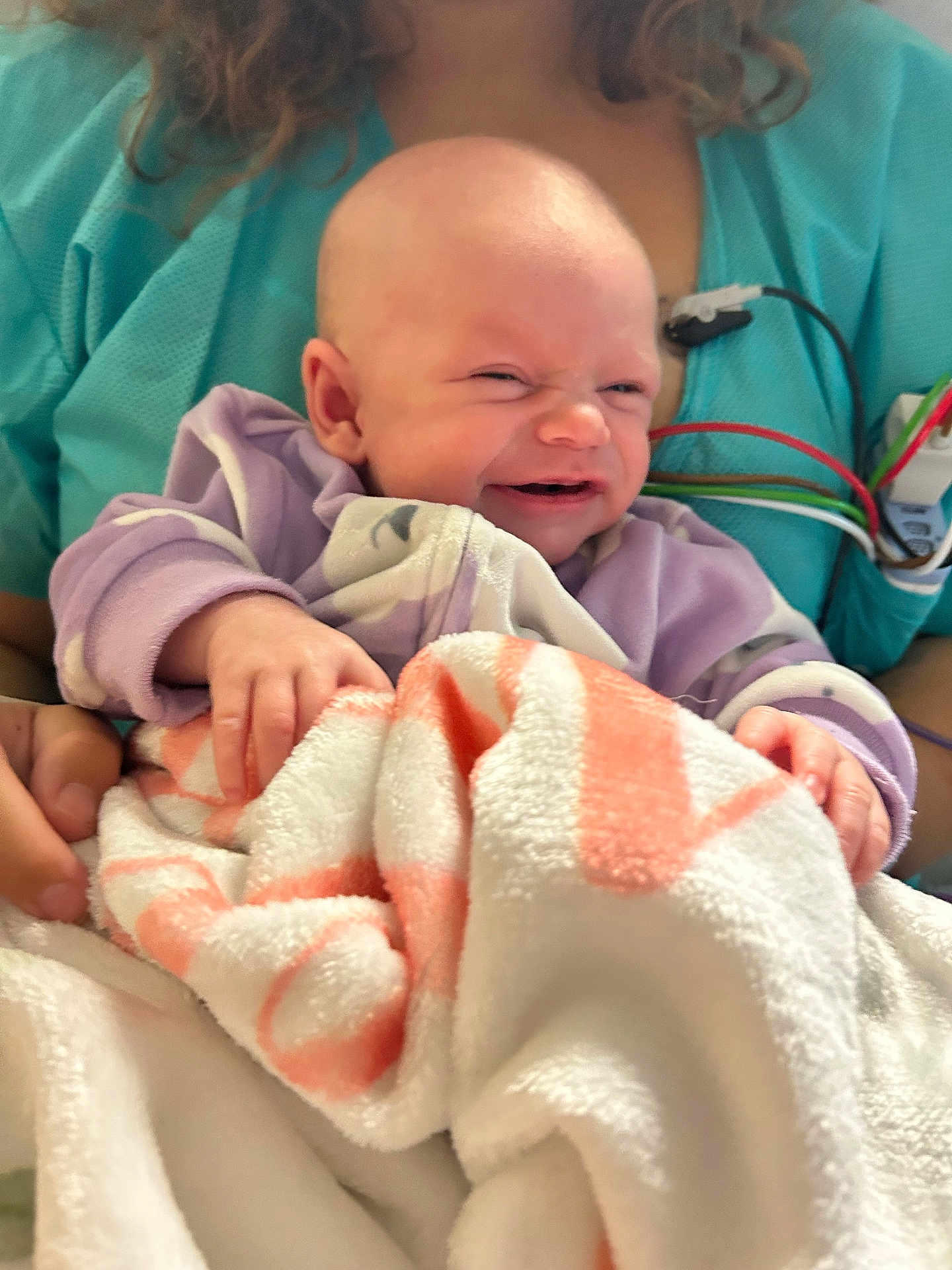 Melody joined the competition — help win amazing prizes! baby, blanket, person, clothing, hand, medical_equipment, scrubs, smile, face, infant, holding, indoor, cute, human, newborn, expression, skin, curly_hair, hospital, comfort