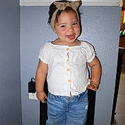 Maeve joined the competition — help win amazing prizes! toddler, child, smiling, headband, white_blouse, blue_jeans, rolled_jeans, standing, indoor, wall, floor, power_outlet, playful, cute, person, portrait, happy, short_hair, casual_clothing, home