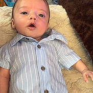 Noah is registered to the contest to win money with this photo: baby, infant, child, striped_shirt, blue_shirt, button_up, blanket, soft_texture, lying_down, wide_eyes, open_mouth, curious, indoor, human, portrait, cute, small_hands, face, head, expression