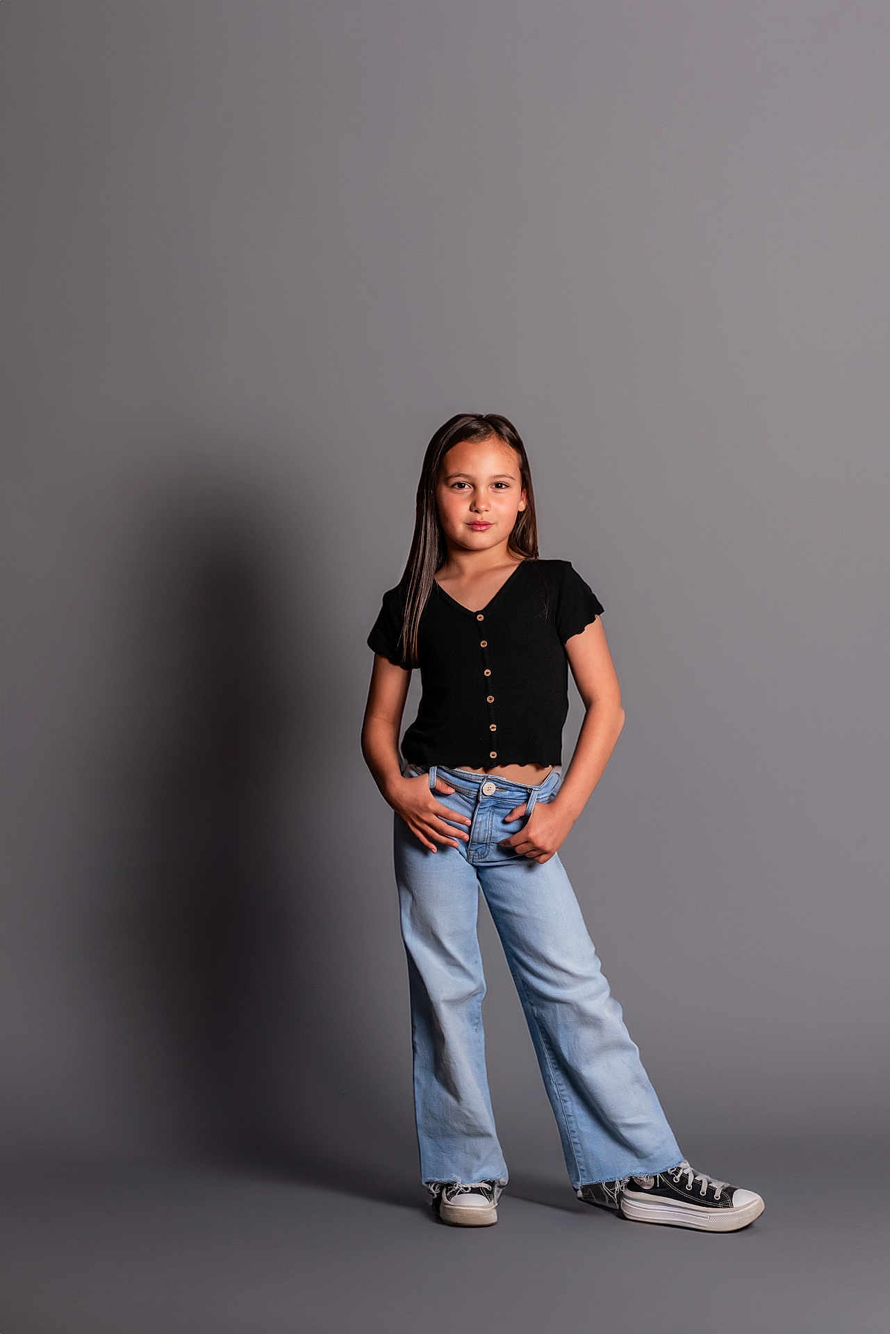 Amy a rejoint le concours — aidez-le/la à gagner de superbes lots ! child, girl, standing, black_top, blue_jeans, sneakers, casual_clothing, studio, gray_background, portrait, smile, long_hair, fashion, hands_on_hips, full_body, shadow, young, confident, pose, indoor
