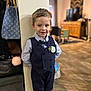 boutonniere, bow_tie, boy, child, cute, dress_shirt, formal_wear, furniture, handbag, home, indoor, living_room, pants, portrait, pose, short_hair, smiling, television, vest, wood_floor