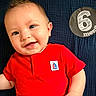 baby, infant, smiling, red_shirt, milestone, 6_months, cute, portrait, child, lying_down, face, happy, close_up, skin, hand, blue_background, texture, young_child, casual_clothing, one_person