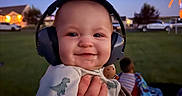 Riot joined the competition — help win amazing prizes! baby, blanket, blurred_background, celebration, child, clothing, dinosaur_print, fireworks, grass, hand, happy, headphones, infant, night, outdoor, park, person, smile, toy, twilight