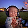Riot joined the competition — help win amazing prizes! baby, headphones, smile, night, fireworks, hand, grass, outdoor, child, dinosaur_print, clothing, person, blurred_background, twilight, celebration, happy, park, blanket, toy, infant