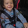 Jakarii is registered to the contest to win money with this photo: toddler, child, car_seat, curly_hair, smiling, happy, seatbelt, animal_print, gray_clothing, car_interior, safety, young_child, cute, daylight, window, nature_outside, casual_wear, baby_trend, portrait, travel