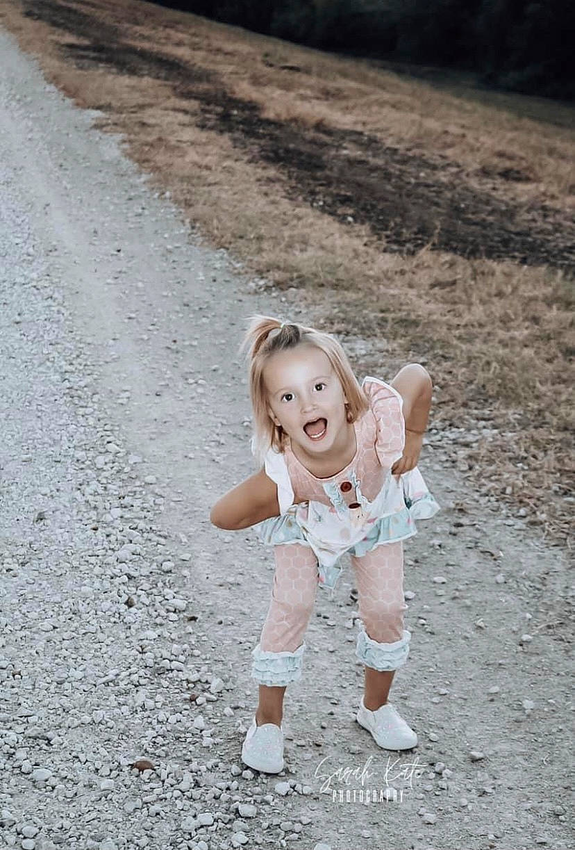 Ansleigh is registered to the contest to win money with this photo: asphalt, blond, child, dress, flash_photography, fun, gesture, grass, happy, human_leg, landscape, people_in_nature, person, recreation, road, road_surface, smile, soil, surprise, toddler