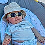baby, child, sunglasses, hat, bucket_hat, clothing, seat, cushion, safety_belt, infant, cute, relaxed, indoor, person, fashion, casual, portrait, smile, hand, foot