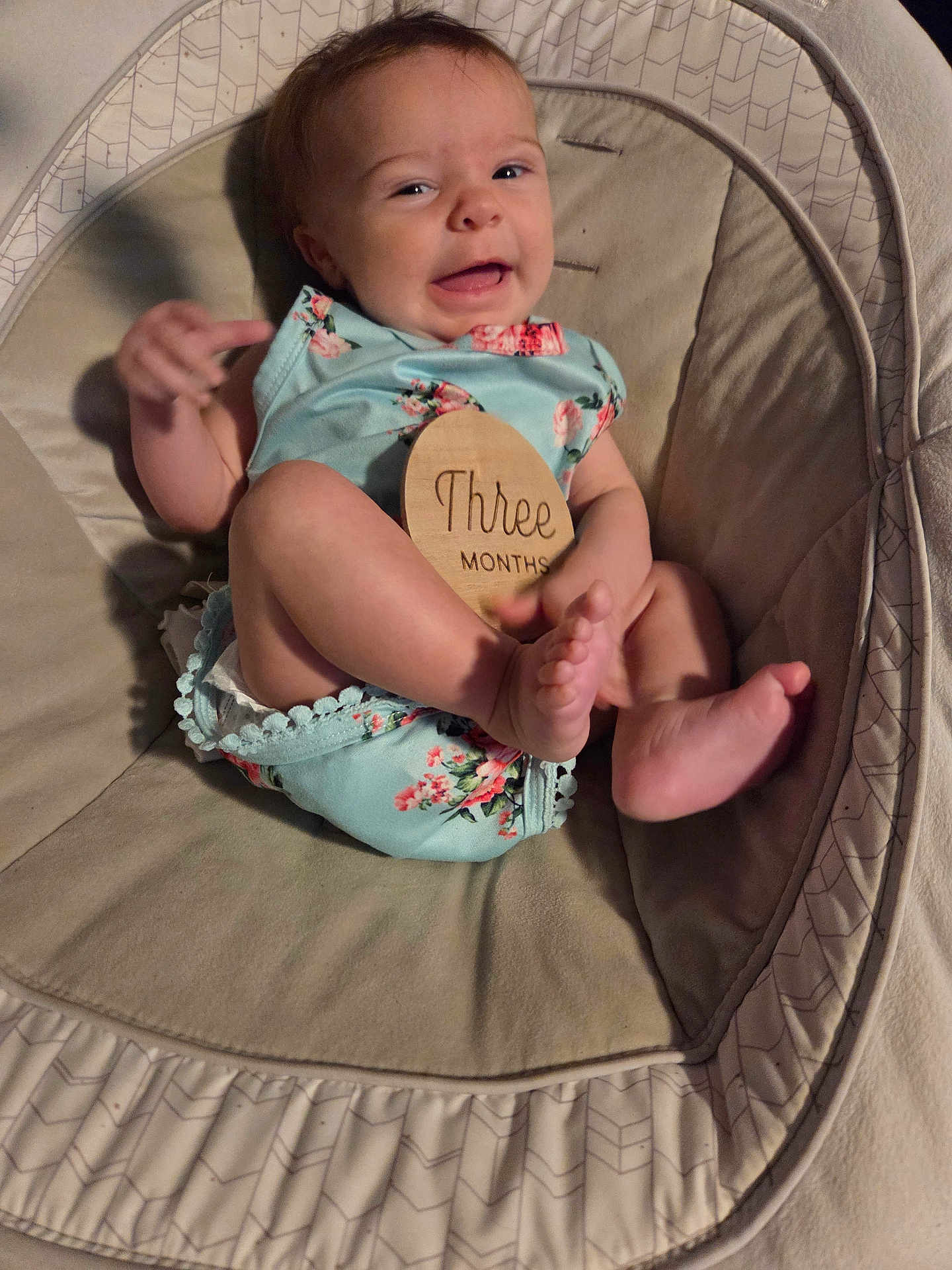 Sophira joined the competition — help win amazing prizes! baby, infant, smiling, onesie, flower_pattern, baby_seat, cushion, wooden_sign, three_months, happy, face, feet, hand, skin, cute, child, indoors, soft_fabric, portrait, person