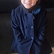 Aaliyah a rejoint le concours — aidez-le/la à gagner de superbes lots ! child, smiling, red_hat, coat, black_shoes, indoor, living_room, furniture, couch, floor, person, portrait, clothing, happy, headwear, shoes, fashion, cute, young, standing