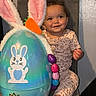 toddler, child, smiling, chair, pajamas, leopard_print, curly_hair, easter_egg, bunny_ears, carrot, colorful_eggs, indoor, wall, foot, cute, happy, holiday, celebration, toy, seat