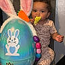 toddler, child, toy, easter_egg, bunny_ears, carrot, colorful_eggs, chair, indoor, curious, playful, pajamas, cute, baby, person, smiling, decorations, holiday, seat, young_child