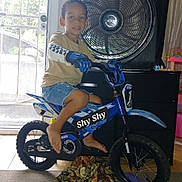 Shyden joined the competition — help win amazing prizes! child, boy, bike, bicycle, indoor, fan, gloves, shorts, tshirt, barefoot, door, screen_door, furniture, carpet, toy, play, smile, helmet_absent, human, portrait