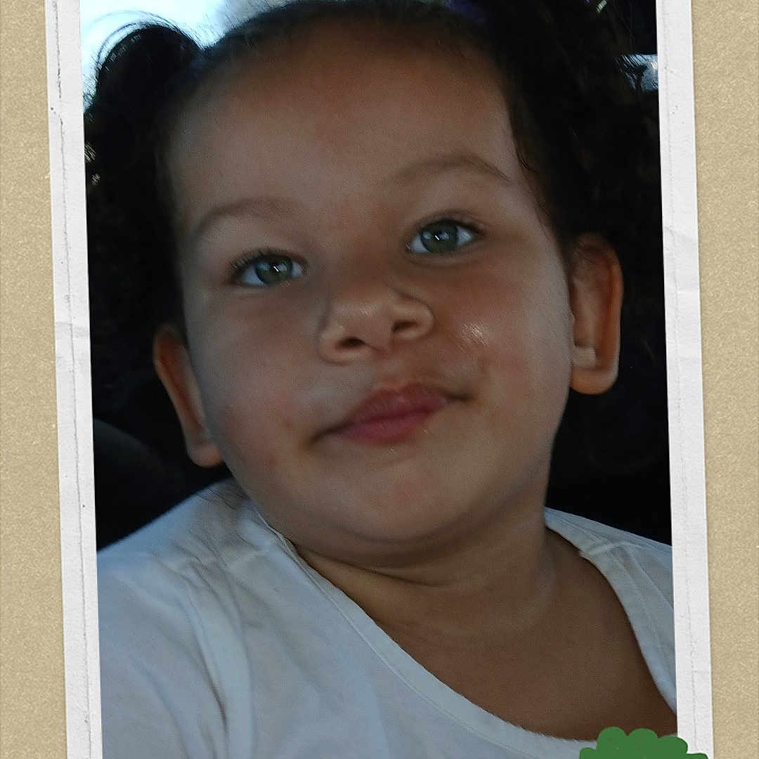 Khloe is registered to the contest to win money with this photo: child, toddler, face, pigtails, white_shirt, car_interior, portrait, smile, ribbon, award, green, hair, cute, young, person, seat, window, daylight, expression, casual