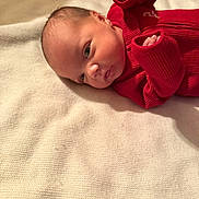 Levi joined the competition — help win amazing prizes! baby, newborn, infant, red_clothing, blanket, lying_down, face, skin, head, eyes, small_hands, soft_texture, warm, cute, portrait, indoors, sleepwear, child, resting, peaceful