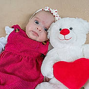 Alicia participe au concours pour gagner de l'argent avec cette photo : baby, infant, teddy_bear, stuffed_animal, red_heart, pink_dress, headband, portrait, lying_down, soft_toy, cute, big_eyes, plush, blanket, close_up, adorable, indoor, child, hand, smile