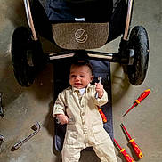 Wyatt participe au concours pour gagner de l'argent avec cette photo : baby, child, concrete_floor, cute, equipment, feet, hands, happy, indoors, infant, mat, mechanic_outfit, playful, repair, screwdrivers, smiling, stroller, tools, workshop, wrenches