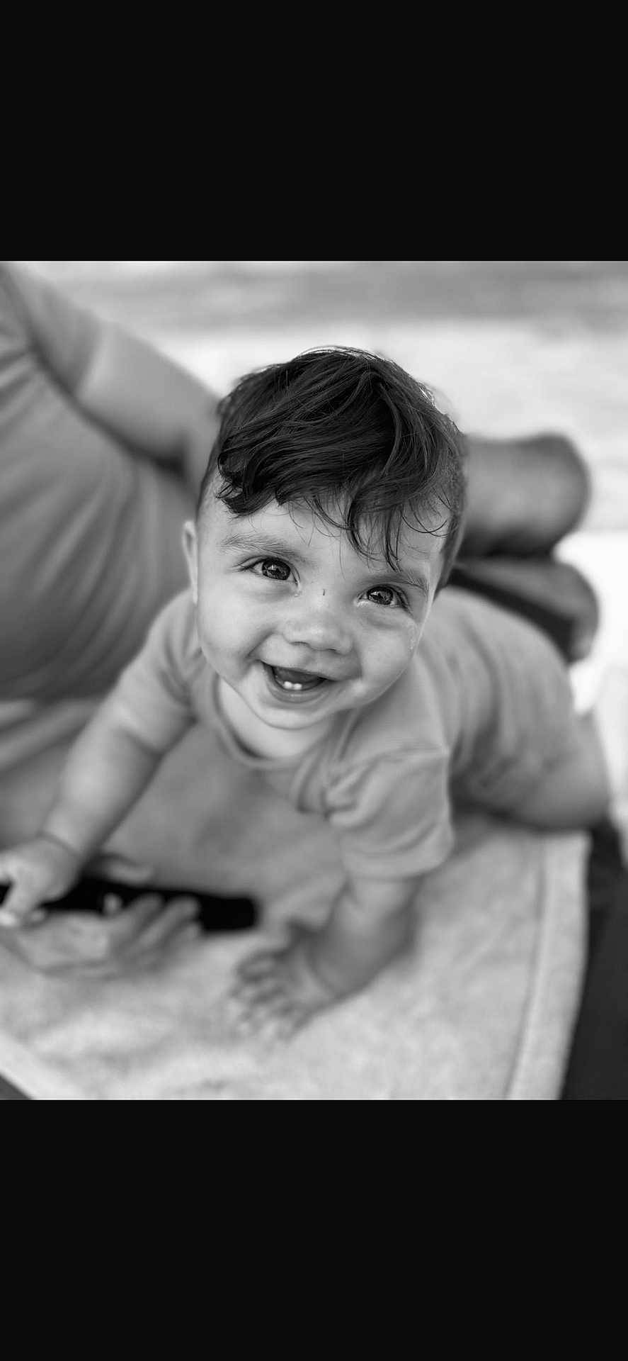 Ronald is registered to the contest to win money with this photo: baby, child, crawling, smiling, happy, face, hair, blanket, person, black_and_white, portrait, cute, infant, indoor, clothing, adult, blurred_background, hand, eyes, expression