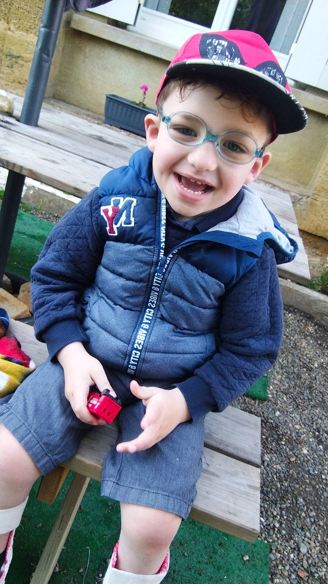 Swan participe au concours pour gagner de l'argent avec cette photo : baseball_cap, cap, child, electric_blue, eyewear, fashion_accessory, fun, grass, happy, joy, knee, lap, leisure, person, personal_protective_equipment, recreation, shorts, sitting, sleeve, smile