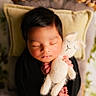 Niall joined the competition — help win amazing prizes! baby, infant, sleeping, portrait, stuffed_animal, bunny, cuddling, cozy, warm_lighting, black_clothing, pillow, blanket, indoors, plants, soft_texture, peaceful, newborn, face, hands, nap