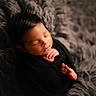 Niall is registered to the contest to win money with this photo: newborn, baby, sleeping, infant, portrait, close_up, bundled, swaddled, black_blanket, fluffy_blanket, tiny_hands, tiny_feet, peaceful, indoors, cozy, soft_lighting, warm_tones, lying_down, photography, face