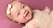 Aubri joined the competition — help win amazing prizes! baby, bow, child, closeup, clothing, cute, face, happy, headband, indoors, infant, lace, lying_down, newborn, person, pink_background, portrait, skin, smiling, soft_background