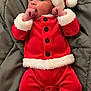 baby, infant, child, santa_outfit, red_clothing, white_fur_trim, hat, blanket, lying_down, cute, holiday, christmas, festive, portrait, face, hands, buttoned_jacket, footed_pants, indoors, cozy
