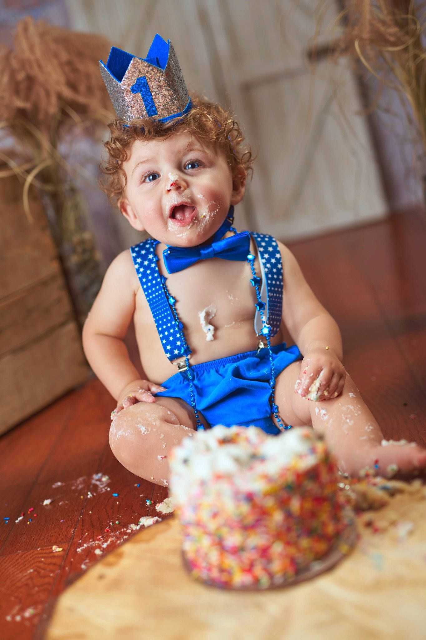 Logan is registered to the contest to win money with this photo: baby_toddler_clothing, blue, cake_decorating, child, costume_hat, cuisine, dessert, dress, event, fashion_design, food, fun, happy, icing, ingredient, jewellery, party_supply, person, smile, sweetness