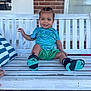 Navari is registered to the contest to win money with this photo: toddler, child, smiling, sitting, bench, white_bench, braided_hair, green_shorts, blue_shirt, sneakers, outdoor, brick_wall, window, happy, portrait, person, footwear, casual_clothing, daylight, front_portrait