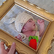 Hayden a rejoint le concours — aidez-le/la à gagner de superbes lots ! baby, infant, knitted_hat, knitted_outfit, carrot, reflection, gold_frame, hand, carpet, portrait, cute, newborn, soft_texture, indoor, baby_clothing, creative, colorful, child, laying_down, cozy
