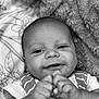 baby, infant, smiling, face, hands, blanket, clothing, striped, cute, portrait, closeup, happy, skin, child, newborn, laying, indoors, soft, black_and_white, expression
